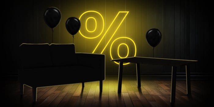 Black sofa and wooden table with black balloons in front of a bright pink percentage symbol on a dark wooden floor.