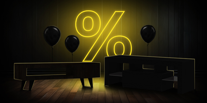 TV stand and black balloons in front of a bright pink percentage symbol on a dark wooden floor.