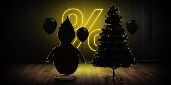 Inflatable Santa figure and Christmas tree with black balloons in front of a bright pink percentage symbol on a dark wooden floor.