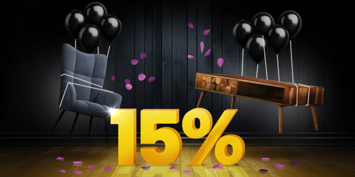 Blue armchair and wooden console table with black balloons in front of a bright yellow 15% sign on a dark wooden floor.