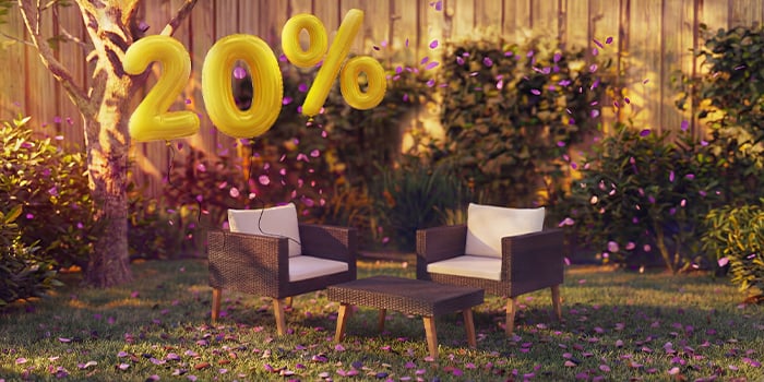 Outdoor rattan lounge chairs with cushions and a small table in a garden setting, decorated with pink confetti and golden 20% discount balloons, highlighting seasonal deals on garden lounge furniture.